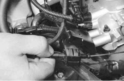 8. Преодолевая сопротивление фиксатора, отсоедините от сектора дроссельного узла наконечник троса…