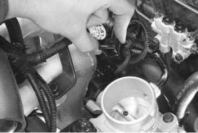 9. Извлеките из прорези в кронштейне трос привода дроссельной заслонки и отведите его в сторону.