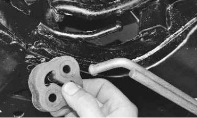 2. Для замены левой подушки дополнительного глушителя сдвиньте подушку с кронштейна рычага...