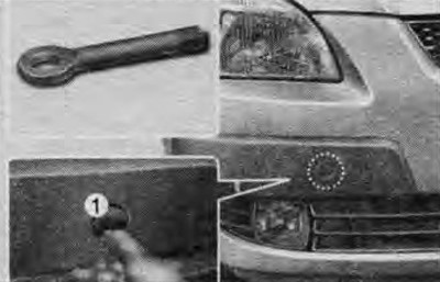 Откройте крышку (1) отверстия для установки буксировочной проушины в переднем бампере: